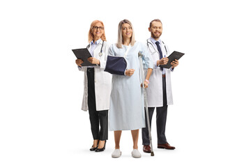 Hospitalized female patient with arm and leg injury standing with a team of doctors