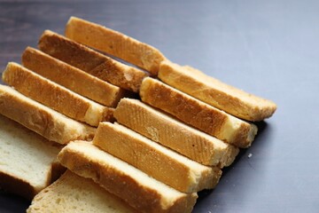 Tea Time Snack. Healthy Wheat rusk served with Indian hot masala tea and milk jug over black background. also known as Mumbai cutting chai. with Copy space. Crunchy rusk or toast.