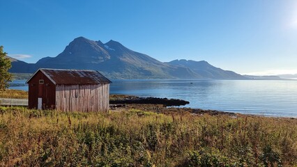 Fototapeta na wymiar pittoresque hut in beautiful scenery at Norwegian fjord with mountains in the background