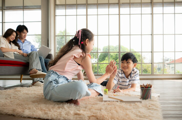 A boy and a daughter from an asian family. The children are having fun in the art of drawing.