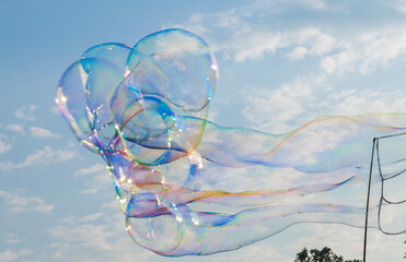 Soap bubbles in the blue sky. Beautifully iridescent balls of soap foam in the air. Background and...