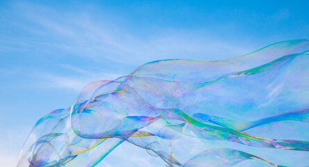 Soap bubbles in the blue sky. Beautifully iridescent balls of soap foam in the air. Background and wallpaper.
