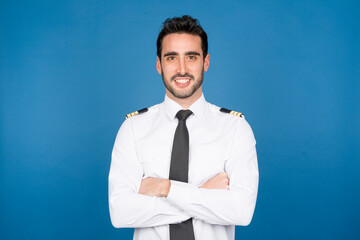 Smiling pilot in studio with crossed arms on blue background © luisrojasstock