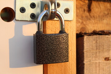 metal padlock on the door of a wooden shed - obrazy, fototapety, plakaty