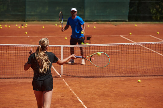 A professional tennis player and her coach training on a sunny day at the tennis court. Training and preparation of a professional tennis player - Powered by Adobe