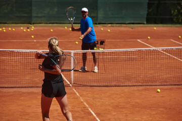 A professional tennis player and her coach training on a sunny day at the tennis court. Training and preparation of a professional tennis player