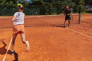 A professional tennis player and her coach training on a sunny day at the tennis court. Training...