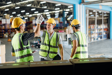 Three warehouse workers using a digital tablet while recording inventory. Logistics employees...