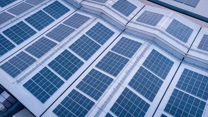 Future green energy and sustainable electricity resource concept. Outdoor focus on solar panels on rooftops or photovoltaics of factories by drone. Industrial roof with solar cell grid with blue tone.