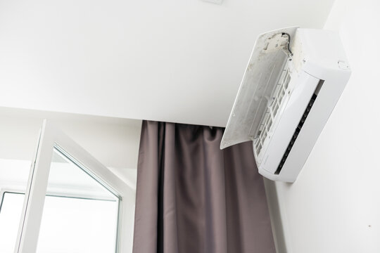 Air conditioner on top of white wall turned on, cooling down room interior during heat wave