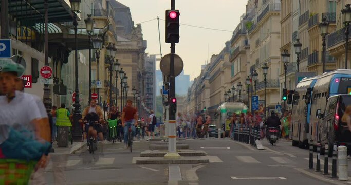 Many bicycles and pedestrians move along the main street of Paris. Heavy traffic on Rivoli street during summer rush hour. Car traffic and pedestrians crossing Rue de Rivoli. Timelapse