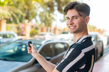 Young handsome man holding car keys with happy expression