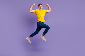 Fototapeta na wymiar Full length of attractive active guy jumping up running fists raised air isolated over violet color background