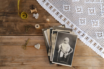 old vintage monochrome photographs scattered on rustic wooden table, dear to heart memorabilia,...