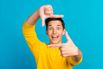 Photo of positive young man hands fingers show cadre toothy smile wear sweater isolated on blue color background