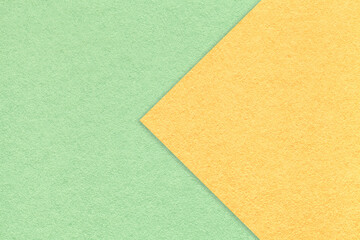 Texture of light green paper background, half two colors with yellow arrow, macro. Structure of craft mint cardboard.