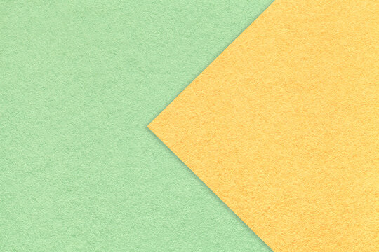 Texture of light green paper background, half two colors with yellow arrow, macro. Structure of craft mint cardboard.