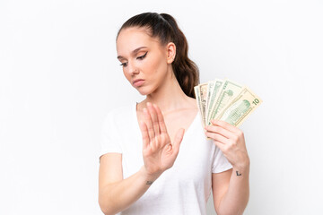 Young caucasian woman taking a lot of money isolated on white background making stop gesture and disappointed