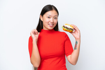 Young Asian woman holding a burger isolated on white background proud and self-satisfied