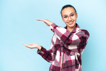 Young Arab woman isolated on blue background holding copyspace to insert an ad