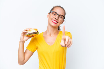 Young caucasian woman holding a burger isolated on white background showing and lifting a finger