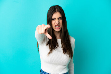 Young caucasian woman isolated on blue background frustrated and pointing to the front