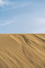 Desert sand hill with wavy sand texture, blu sky.