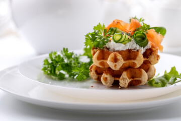 Belgian waffles with red fish and greens on a white dish on a white background