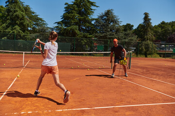 A professional tennis player and her coach training on a sunny day at the tennis court. Training and preparation of a professional tennis player