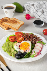 Healthy romantic breakfast - heart-shaped fried eggs served with avocado, spinach, quinoa, cherry tomatoes, radish and olives on white plate