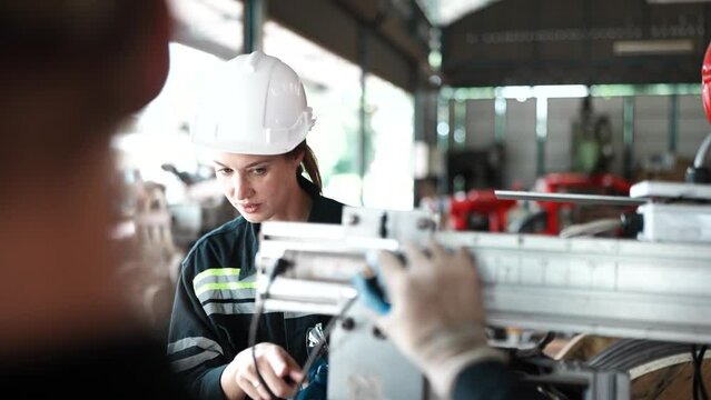 Worker operating in manual lathe.   industrial Engineer manager man demonstration and training mechanic worker woman operating industrial lathe machine and checking quality control