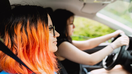Fototapeta na wymiar Couple of two young girls and friends, traveling by car, one of them with dyed orange hair, enjoy a weekend getaway in Spain