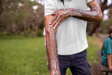 Close-up of aboriginal man applying traditional body paint to his arm