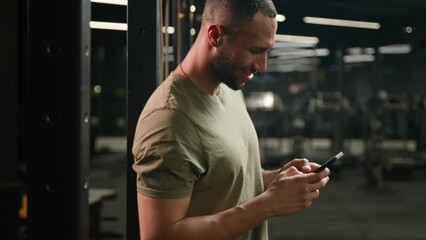 African American fitness man athlete sport trainer smiling laughing reading funny news watching humorous video joke in smartphone sportsman browsing mobile phone laugh looking at camera smile in gym