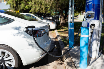 Electric vehicle fast charger with EV car plugged in to charge up on road trip
