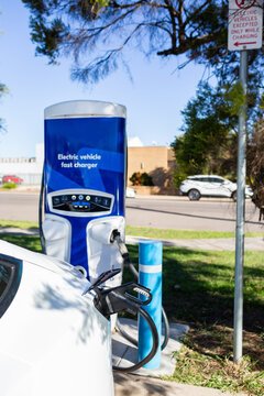 Electric vehicle fast charger with EV car plugged in to charge up on road trip