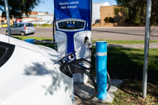 Electric vehicle fast charger with EV car plugged in to charge up on road trip