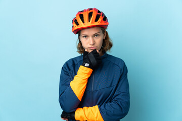 Young cyclist woman isolated on blue background thinking