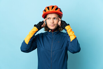 Young cyclist woman isolated on blue background having doubts and thinking