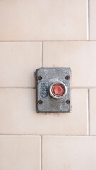 Botón rojo retro en pared de baldosa
