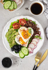Healthy romantic breakfast - heart-shaped fried eggs served with avocado, spinach, quinoa, cherry tomatoes, radish, cucumber and olives on white plate, Top view
