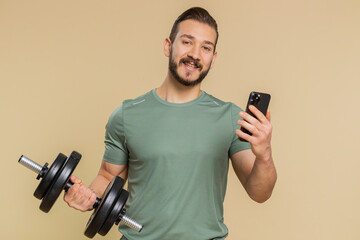 Fototapeta na wymiar Athlete sportive man texting share messages content on smartphone social media applications online, sms message, browsing, reading news. Middle eastern sportsman guy with dumbbell on beige background