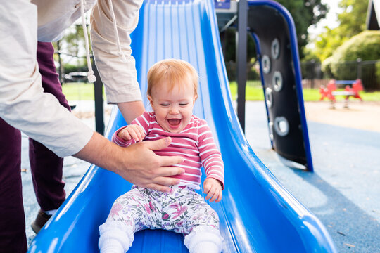 Baby Laughing And Being Caught By Father At Playground Slippery Dip