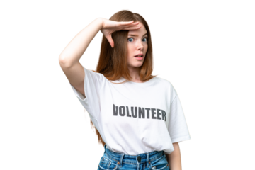 Young volunteer woman over isolated chroma key background doing surprise gesture while looking to the side