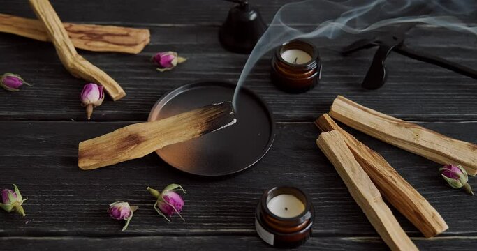 Palo Santo stick burning on ceramic holder, Mexican palo santo aromatherapy, sacred wood placed on stand, scented candles on wooden table, smoke spreading, 4k footage, video for relaxation