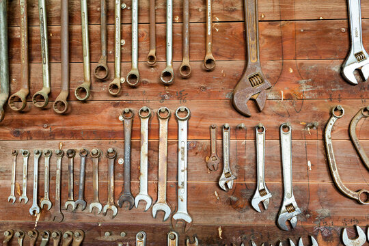 Rust speckled tools hanging neatly in place on farm shed wall