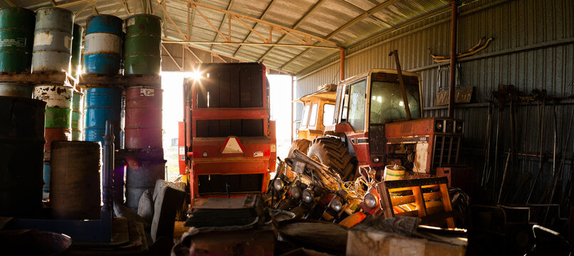 Old farm machinery parked in dark shed left to rust and forgotten in time
