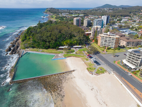 Aerial view of an ocean bath alongside a white sandy beach and waterfront buildings