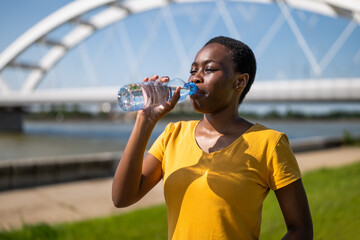 Woman drinking water while exercise outdoor..	