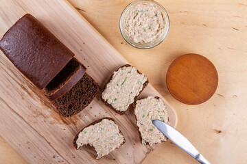 Spread carefully placed on dark bread, resting on wooden cutting board situated on wooden countertop